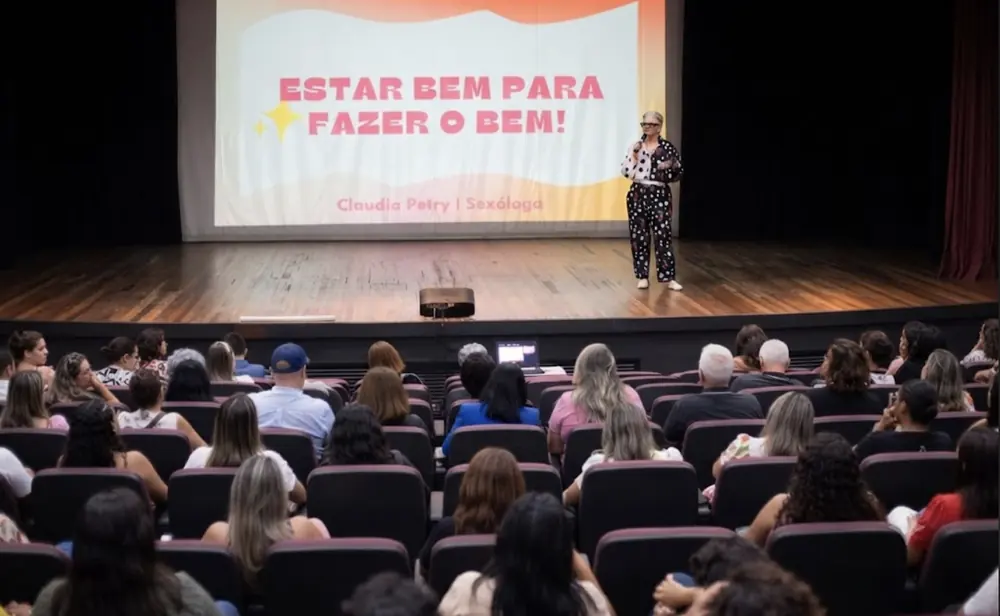 Claudia Petry palestrando no palco com o tema Estar bem para fazer o bem